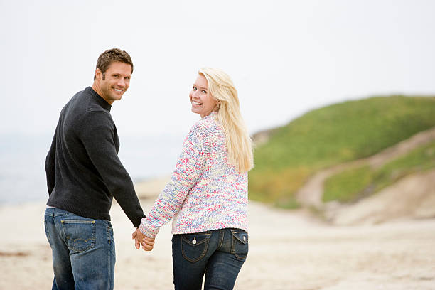 istock Couple walking at beach holding hands smiling 452765699