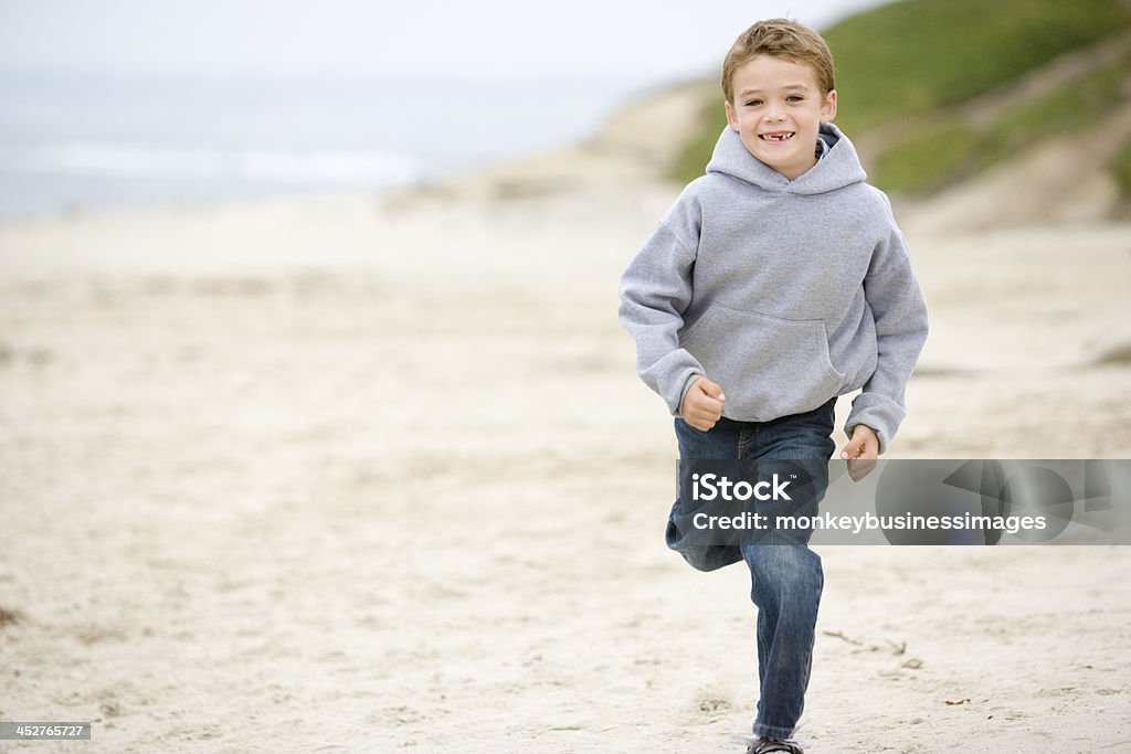 Young boy running on beach smiling Young boy running on beach towards camera smiling Boys Stock Photo