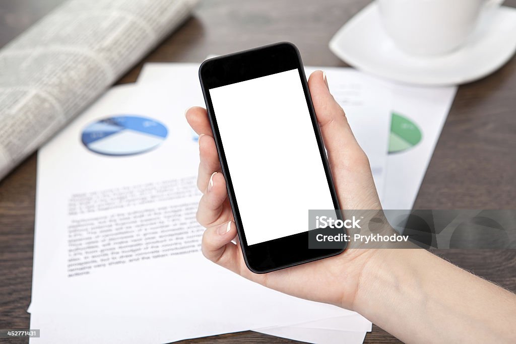 Kobieta Ręka trzyma telefon na stole z grafiką - Zbiór zdjęć royalty-free (Arkusz kalkulacyjny)