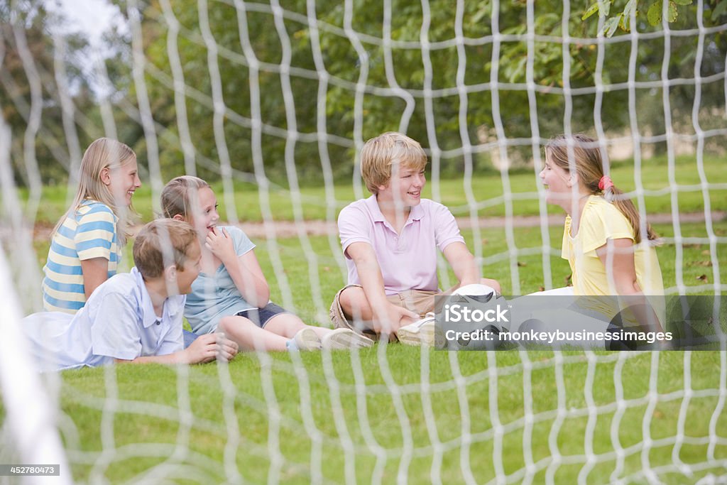 Cinque giovani amici in campo da calcio di parlare e sorridere - Foto stock royalty-free di Allegro
