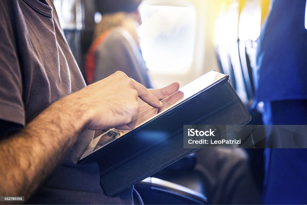 Hombre usando comprimido durante el vuelo. - Foto de stock de Actividades bancarias libre de derechos