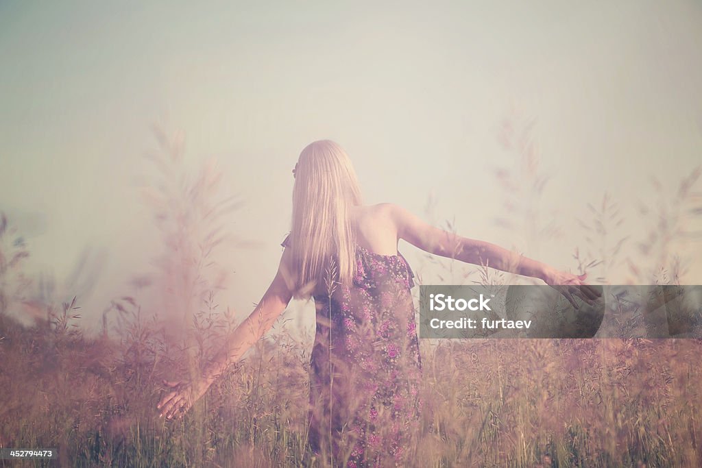 Girl having fun in summer field Retro toned portrait of young girl in summer field from back Agricultural Field Stock Photo