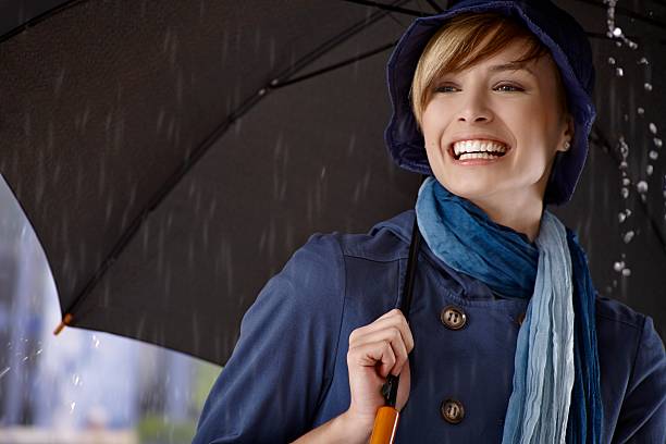 Giovane donna con ombrello in pioggia - foto stock