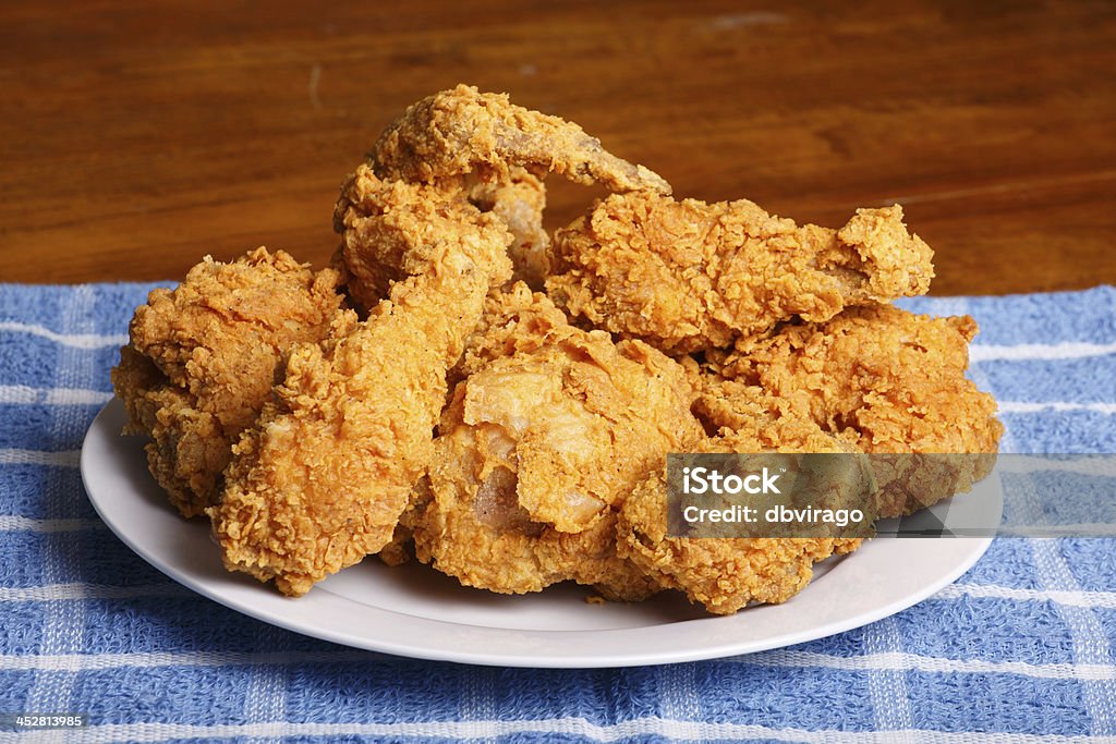 Plate of Fried Chicken on Blue Plaid Towel A plate of fresh, hot, crispy fried chicken on a blue plaid towel on a wood table Fried Chicken Stock Photo