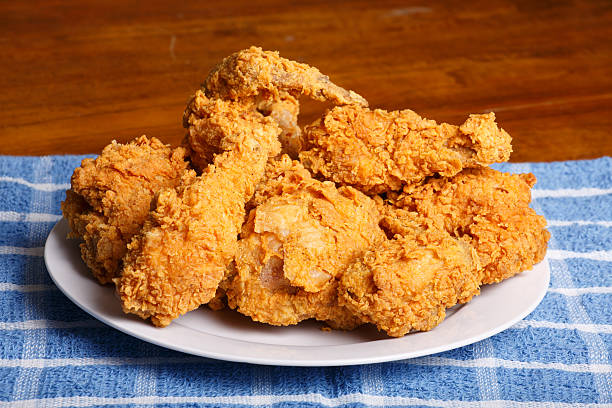 Plate of Fried Chicken on Blue Plaid Towel A plate of fresh, hot, crispy fried chicken on a blue plaid towel on a wood table FRIED CHICKEN stock pictures, royalty-free photos & images