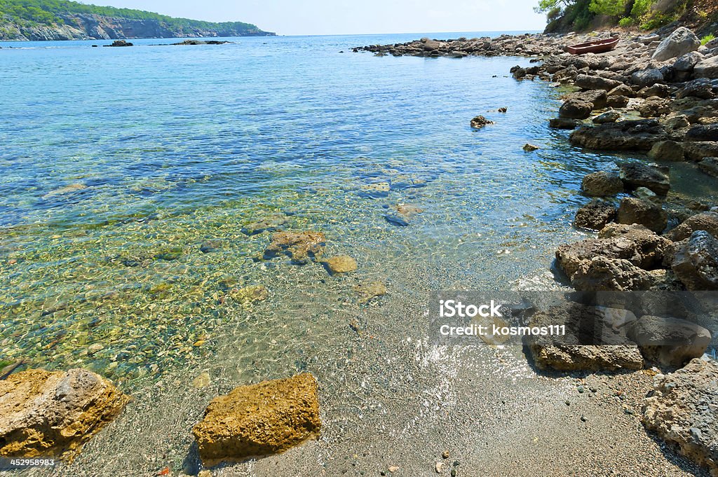 boulders on the shore of a clean and calm sea At The Edge Of Stock Photo