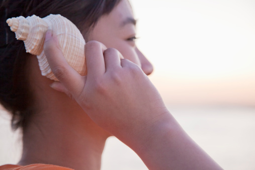 Teenage girl listening to seashell, close-up