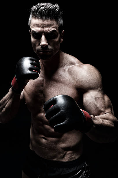 MMA fighter MMA fighter posing in front of black background combat sport stock pictures, royalty-free photos & images