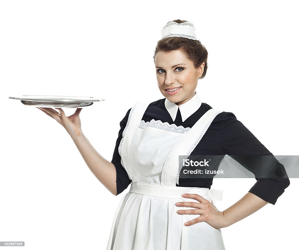 Victorian Style Maid Portrait of vintage maid holding a tray and smiling at camera. Studio shot, white background. Waiter Stock Photo