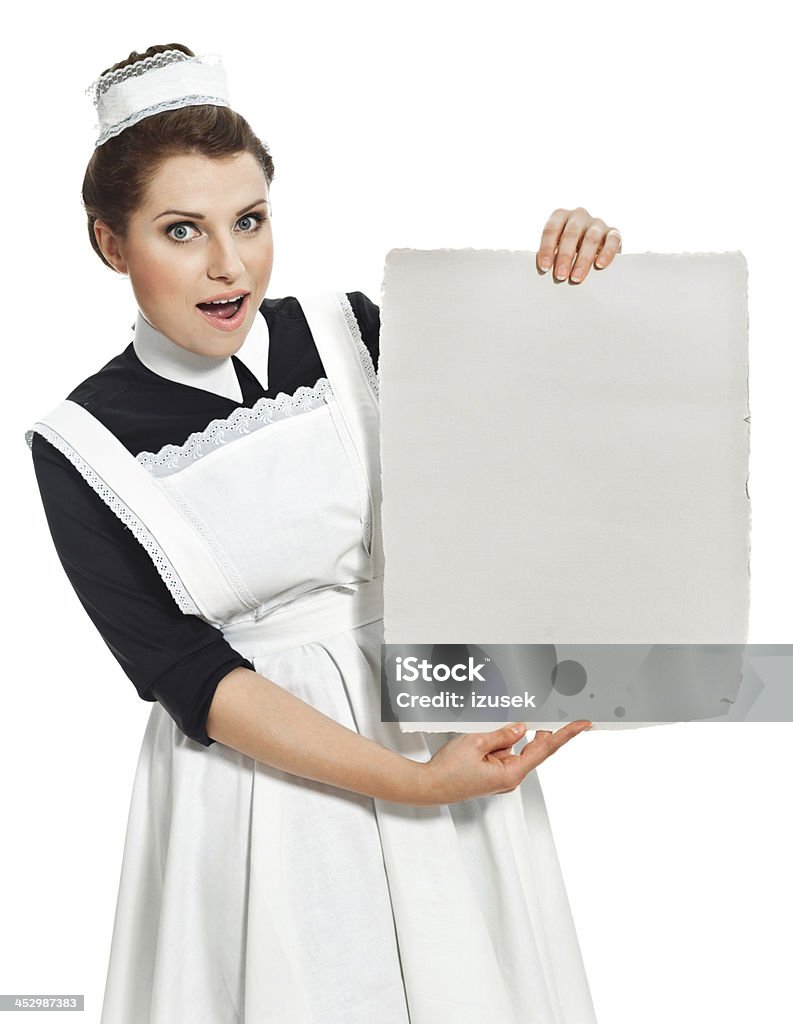 Victorian style Maid with announcement Portrait of surprised retro maid holding piece of paper and looking at the camera. Studio shot, white background. 1920-1929 Stock Photo