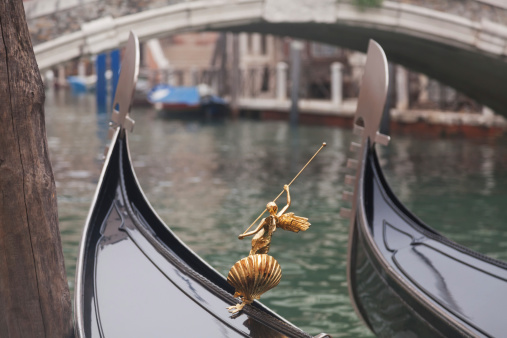 Two gondola in Venice near pier and golden figurine