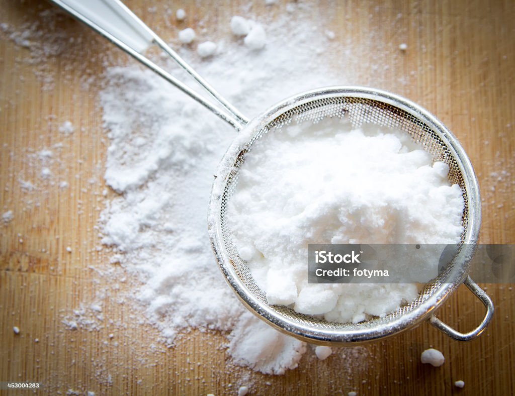 Powdered sugar in a sifter ready for dusting icing sugar on old wooden background Powdered Sugar Stock Photo