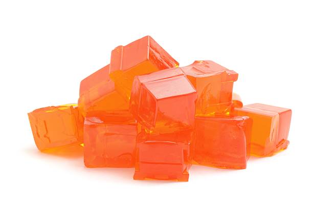 Orange Jelly Cubes A heap of  concentrated orange jelly cubes isolated on a white background. gelatin dessert stock pictures, royalty-free photos & images