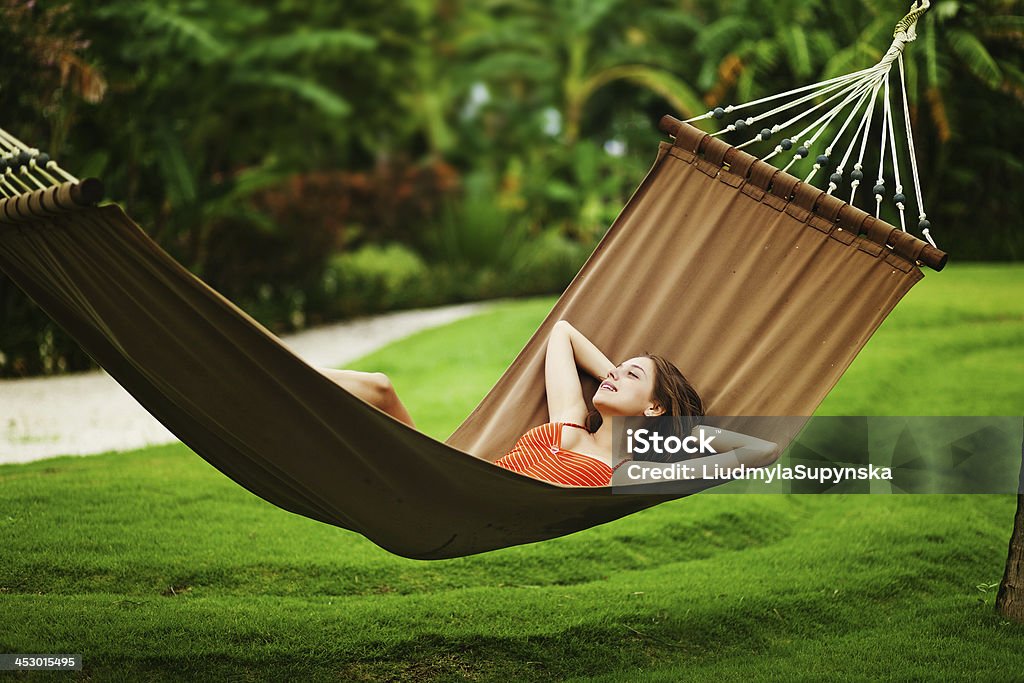 Woman relaxing in outdoor hammock over green grass Young beautiful woman in hammock, Bali, Indonesia Adult Stock Photo