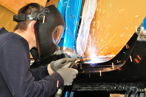 Proffesional worker welding car body.