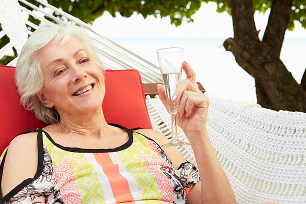 istock Senior Woman Relaxing In Beach Hammock With Champagne 453023789