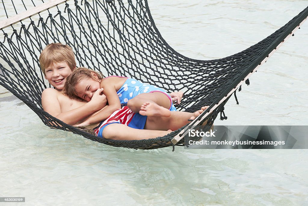 Fratello e sorella rilassarsi In spiaggia sull'amaca - Foto stock royalty-free di Affettuoso