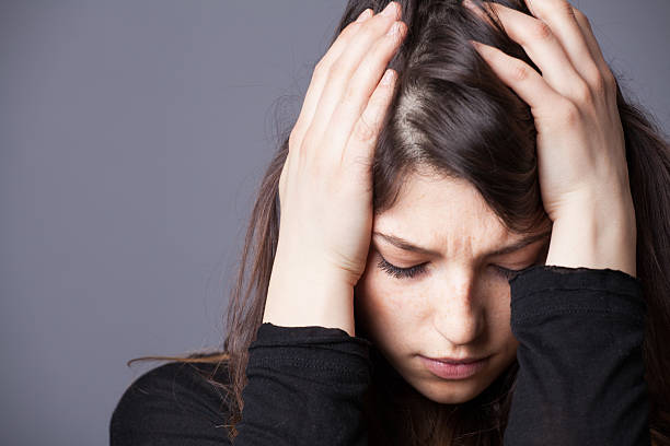 Frustrated young woman holding her head in her hands This young woman is going through some tough times seasonal affective disorder stock pictures, royalty-free photos & images