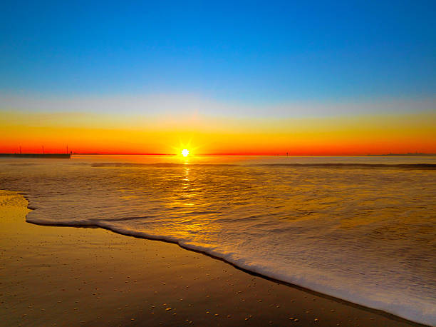 istock Blue and orange skies at sunrise viewed from a sandy beach 453031829