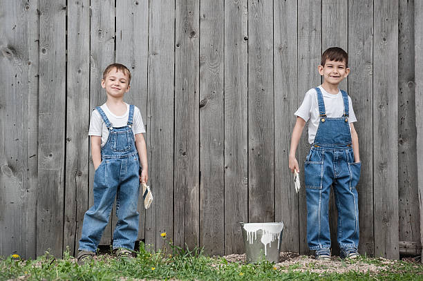 boys with brushes and paint at an old wall - 工人褲 個照片及圖片檔