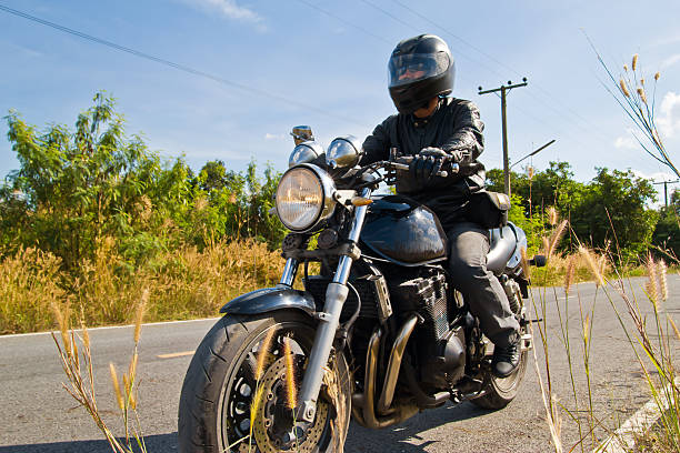 Motorcyclist on asphalt country road view of a man with a motorcycle on a asphalt road. motorcycle biker stock pictures, royalty-free photos & images