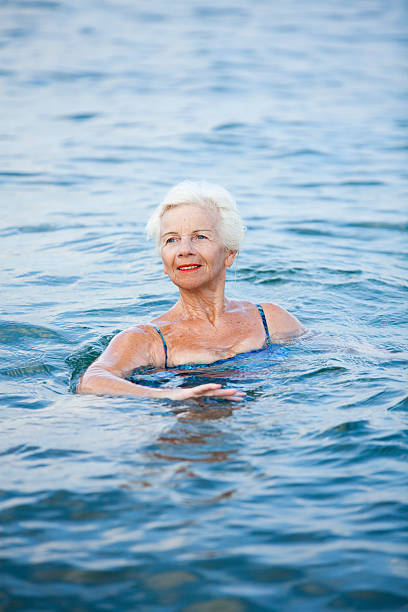 istock Beautifil elderly woman doing exercises in water 453044383