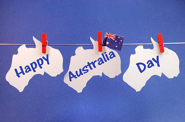 Celebrate Australia Day holiday on January 26 with a Happy Australia Day message greeting written across white Australian maps and flag hanging from pegs on a line against a blue background.