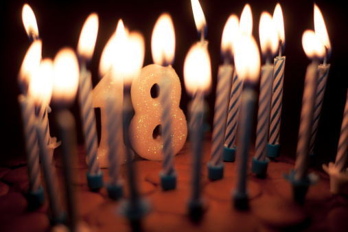 Birthday cake with lit candles including '18' candle