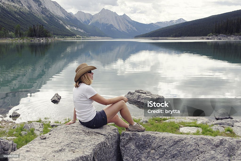 Kobieta siedzi na skraju leku Lake - Zbiór zdjęć royalty-free (Alberta)