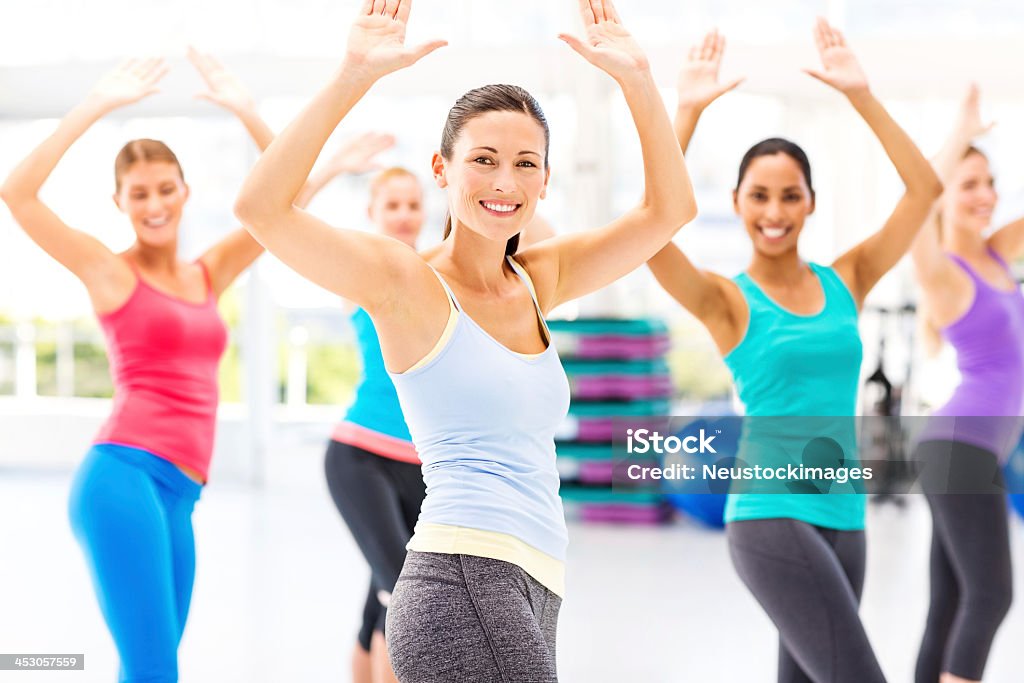 Female Instructor With Customers Practicing Aerobic Dance In Health Club Portrait of young female instructor with customers practicing zumba in health club. Horizontal shot. Zumba Stock Photo