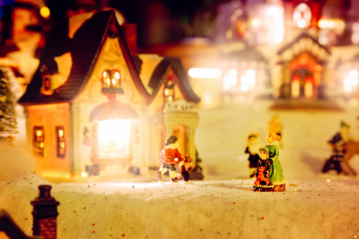 Christmas miniature village scene with small figurines and illuminated houses.