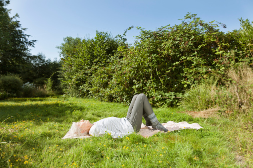 senior woman exercising in garden at summer, layig on ground