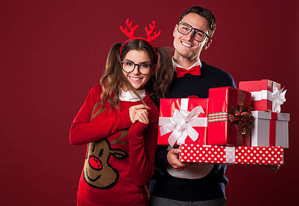 Smiling couple holding stack of christmas gifts Smiling couple holding stack of christmas gifts  vintage nerd with reindeer sweater stock pictures, royalty-free photos & images