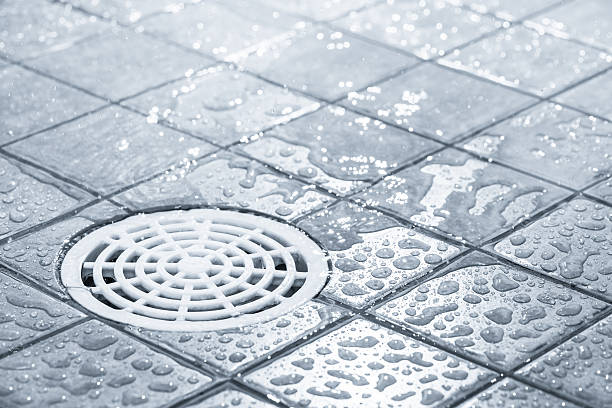 Water draining off after a shower Floor drain, running water in shower, tinted black and white image sewer drain stock pictures, royalty-free photos & images