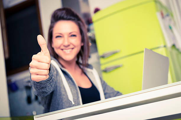 Young woman giving a thumbs up while on her laptop stock photo