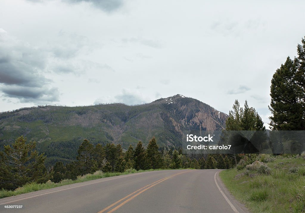 Estrada curva até as montanhas do Parque Nacional de Yellowstone.  Espaço para texto. - Foto de stock de Arco natural royalty-free