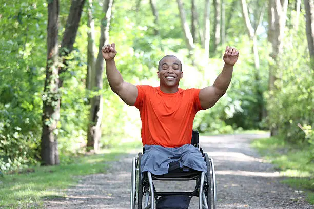 young african man in wheelchair cheering outdoors