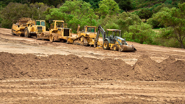 Earthwork Site and Equipment Bulldozers, graders and backhoes parked at a grading project site. Earthmoving stock pictures, royalty-free photos & images