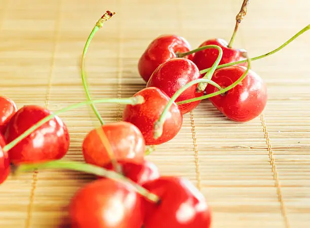 Group of cherries placed on bamboo tablecloth.Small depth of field with cross processing.