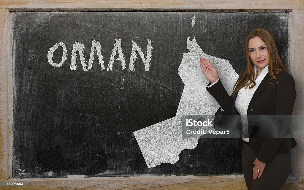 Teacher showing map of oman on blackboard Successful, beautiful and confident young woman showing map of oman on blackboard for presentation, marketing research and tourist advertising Adult Stock Photo