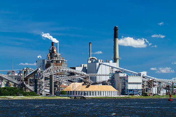 A horizontal view of an industrial paper mill on a river