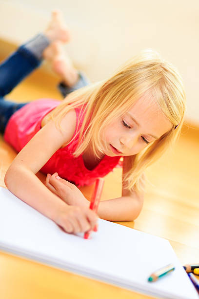 little blonde girl drawing en la sala de estar - schoolgirl little girls crayon human face fotografías e imágenes de stock