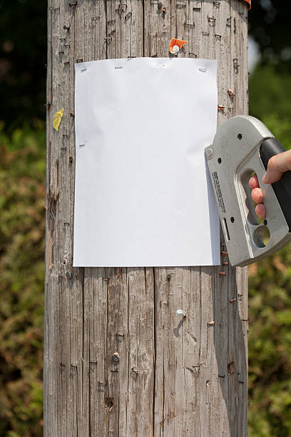 stapling a blank sign stapling a blank sign on telephone post stapled paper stock pictures, royalty-free photos & images