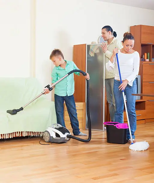 Middle-aged couple with teenage boy doing house cleaning