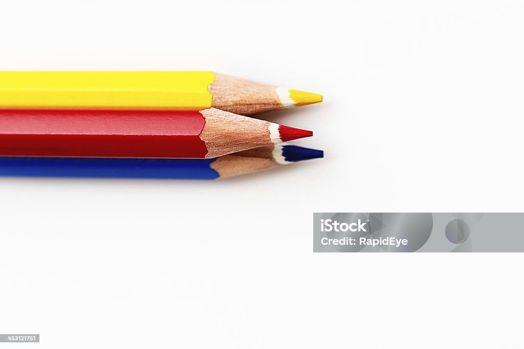 Primary-colored trio of pencil crayons on white All the primary colors: red, yellow, and blue pencil crayons stacked up in a pyramid on a white surface, possibly a sketchpad. Plenty of copy space for your message. Art and Craft Equipment Stock Photo