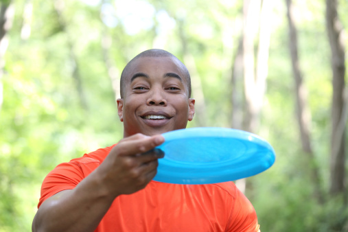 young african male playing frisbee at the park