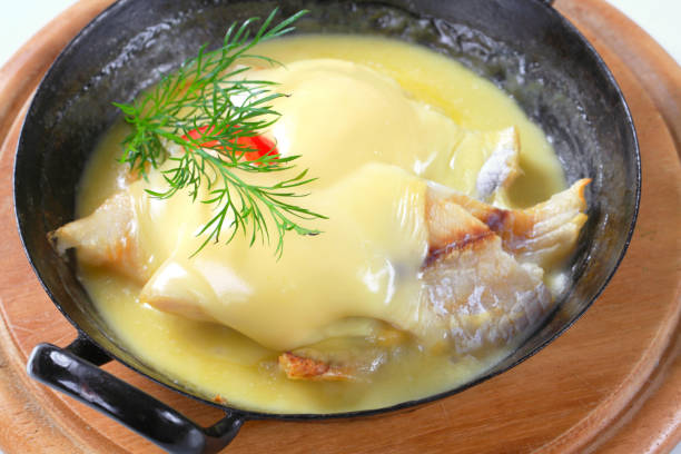 フライパンで焼いた魚のチーズのソースがけ - hollandaise sauce ストックフォトと画像
