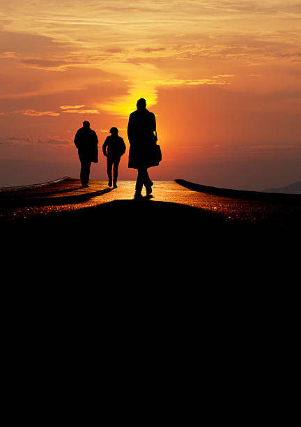 istock silhouetted people walk over bridge in sunset 453124161