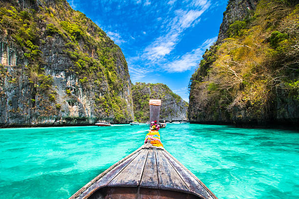 A wooden boat sailing near phi island in Thailand Traditional wooden  boat in a picture perfect tropical bay on Koh Phi Phi Island, Thailand, Asia. koh tao thailand stock pictures, royalty-free photos & images