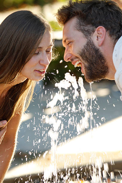 Happy young couple enjoys drinking of water from fountain stock photo
